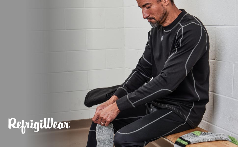Man in locker room putting on socks wearing RefrigiWear's Heavy Weight Mid Layers