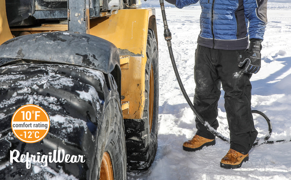 Man standing next to a tractor in the snow wearing RefrigiWear Insulated Softshell Pants